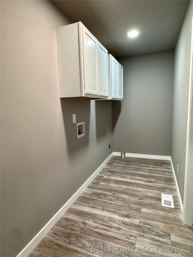 washroom with visible vents, wood finished floors, cabinet space, baseboards, and hookup for a washing machine