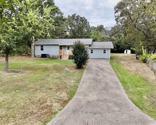 view of front of property with central air condition unit, a front yard, and fence