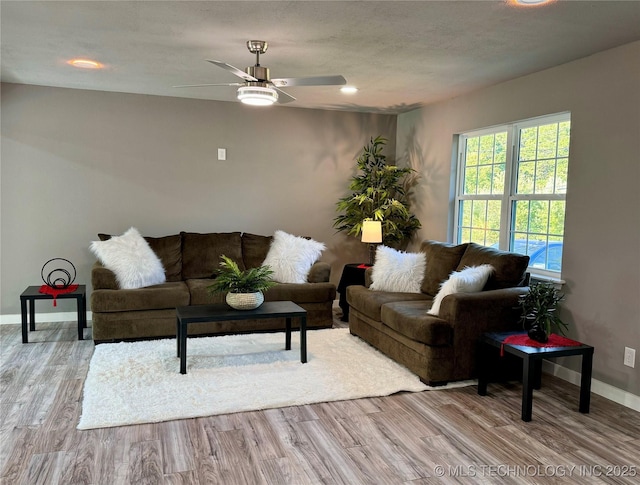 living area with ceiling fan, baseboards, and wood finished floors