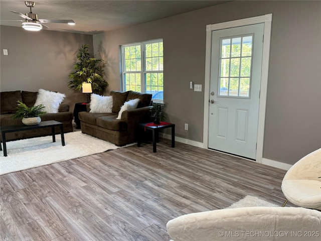 living area with baseboards, light wood-type flooring, and ceiling fan