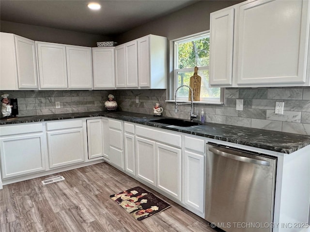 kitchen with visible vents, white cabinetry, a sink, decorative backsplash, and stainless steel dishwasher