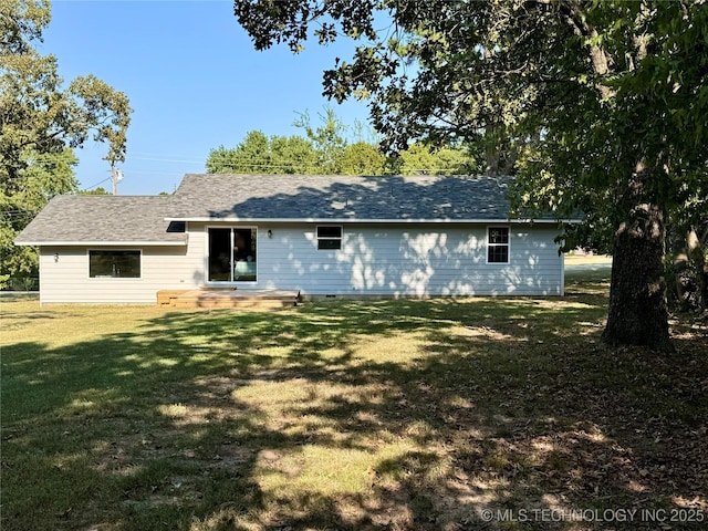 back of house featuring a lawn and a shingled roof