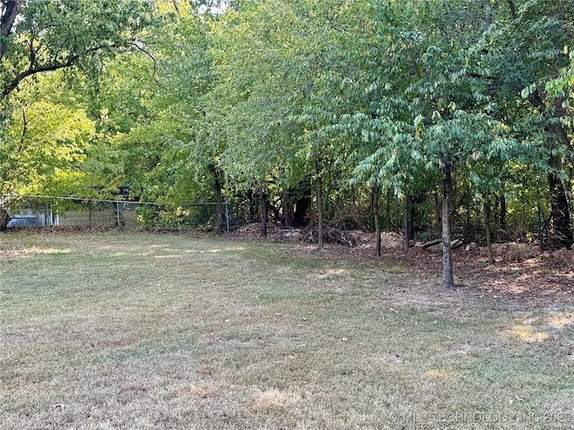 view of yard featuring a wooded view and fence