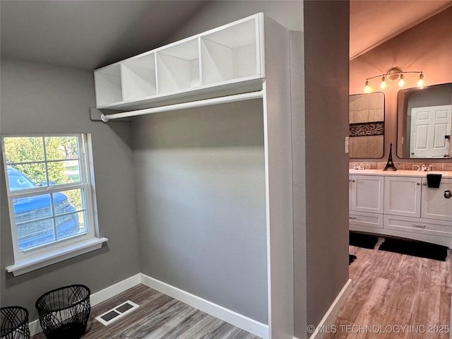 spacious closet featuring lofted ceiling, wood finished floors, visible vents, and a sink