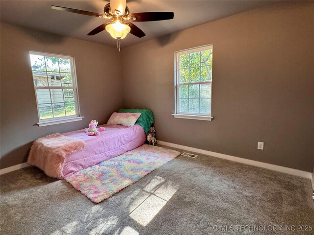 carpeted bedroom with visible vents, multiple windows, a ceiling fan, and baseboards