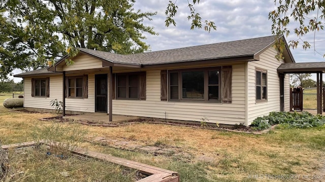 view of front of property with a front yard, a patio area, and roof with shingles