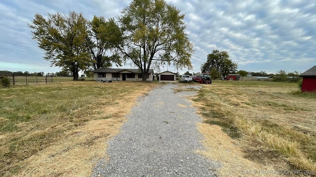 view of front facade featuring driveway, an attached garage, and fence