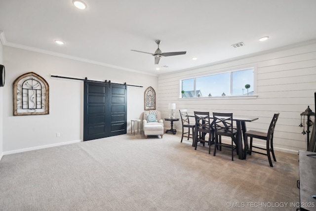 dining room with a barn door, carpet flooring, crown molding, and visible vents