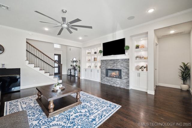 living room featuring crown molding, stairway, built in shelves, and a fireplace