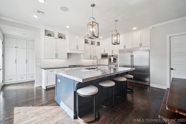 kitchen featuring visible vents, a center island with sink, a sink, white cabinetry, and appliances with stainless steel finishes