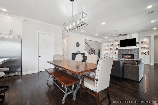 dining space featuring visible vents, a ceiling fan, a fireplace, and crown molding