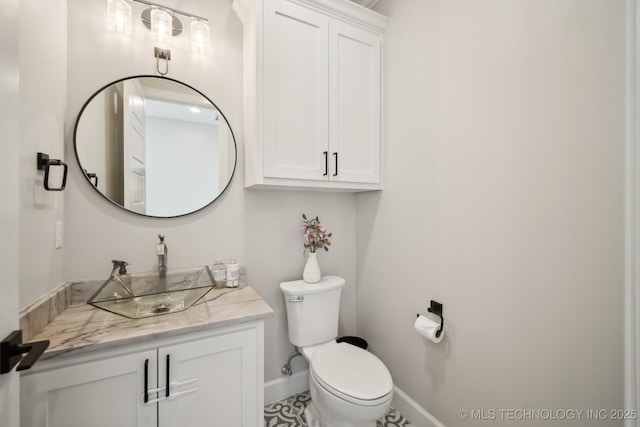 bathroom with toilet, vanity, and baseboards