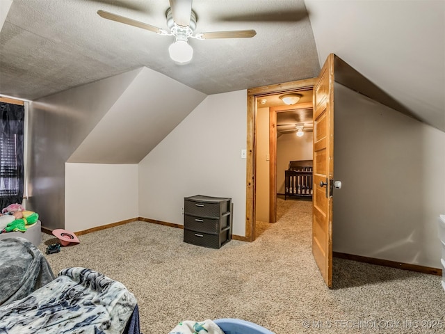 interior space featuring a ceiling fan, a textured ceiling, carpet flooring, baseboards, and vaulted ceiling