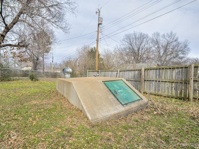 entry to storm shelter with a yard and a fenced backyard