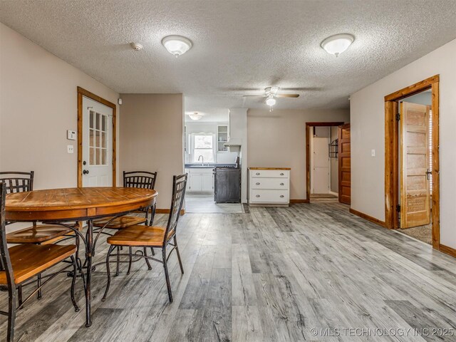 dining area featuring a textured ceiling, baseboards, light wood-style floors, and a ceiling fan