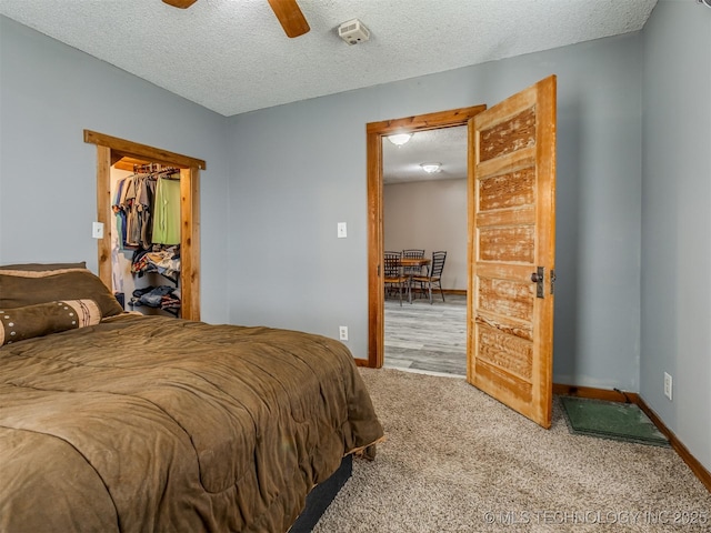 bedroom featuring ceiling fan, carpet, baseboards, and a textured ceiling