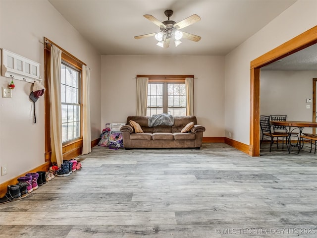 living room featuring a ceiling fan, baseboards, and wood finished floors