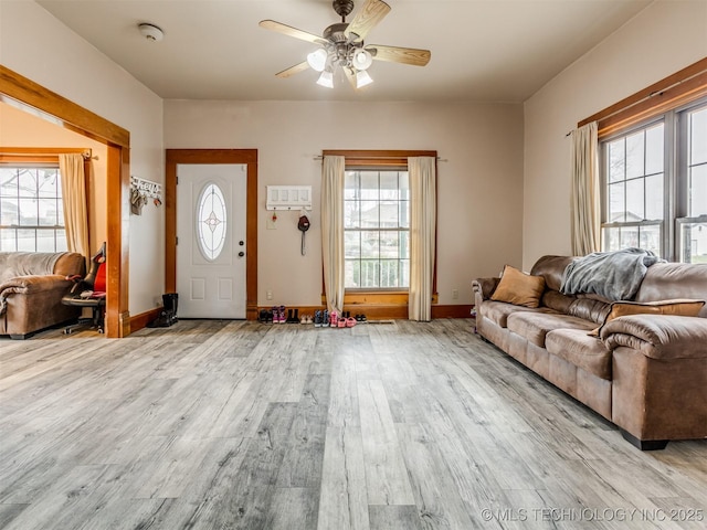 living area with a ceiling fan, wood finished floors, and baseboards