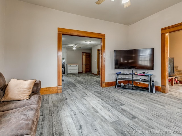 living area with wood finished floors, baseboards, and ceiling fan