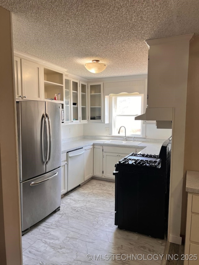 kitchen with a sink, freestanding refrigerator, white dishwasher, light countertops, and black range with gas stovetop