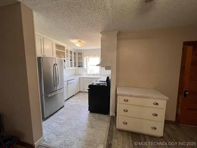 kitchen featuring black range with gas stovetop, freestanding refrigerator, white dishwasher, marble finish floor, and a sink