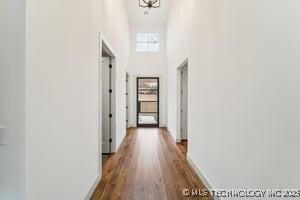 corridor featuring dark wood-style flooring and a towering ceiling