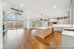 kitchen featuring a center island with sink, wood finished floors, open floor plan, a fireplace, and ceiling fan