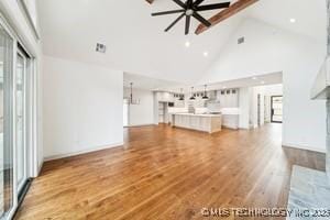 unfurnished living room with a ceiling fan, wood finished floors, and high vaulted ceiling