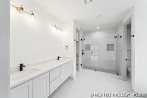 full bath with a sink, double vanity, and a shower stall