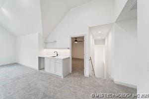 bonus room featuring light colored carpet, lofted ceiling, and a sink