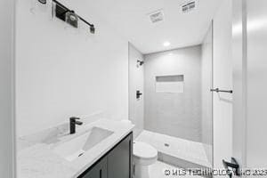 bathroom featuring visible vents, toilet, walk in shower, and vanity