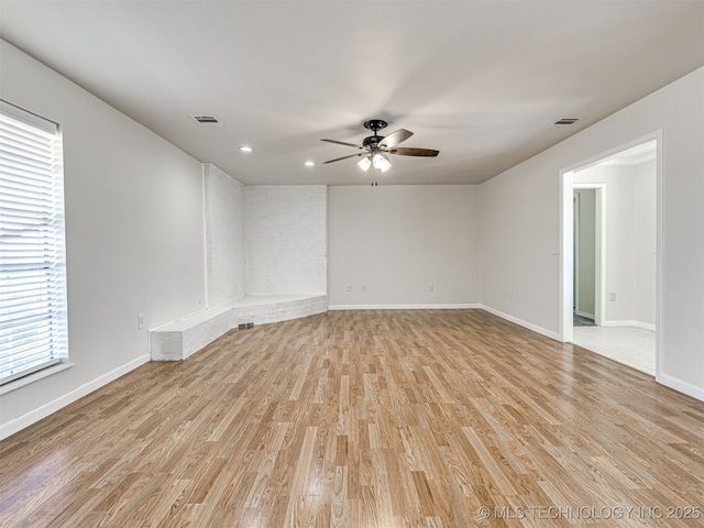 empty room featuring light wood finished floors, visible vents, baseboards, and ceiling fan