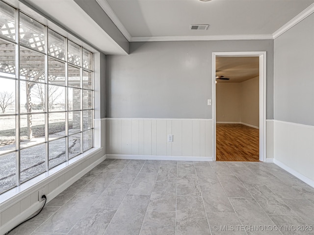 unfurnished room featuring a wainscoted wall, crown molding, visible vents, and a wealth of natural light