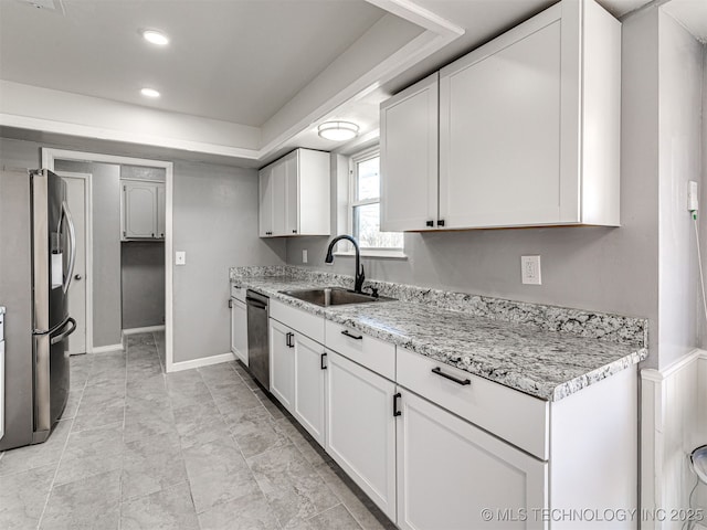 kitchen featuring a sink, stainless steel appliances, baseboards, and white cabinets