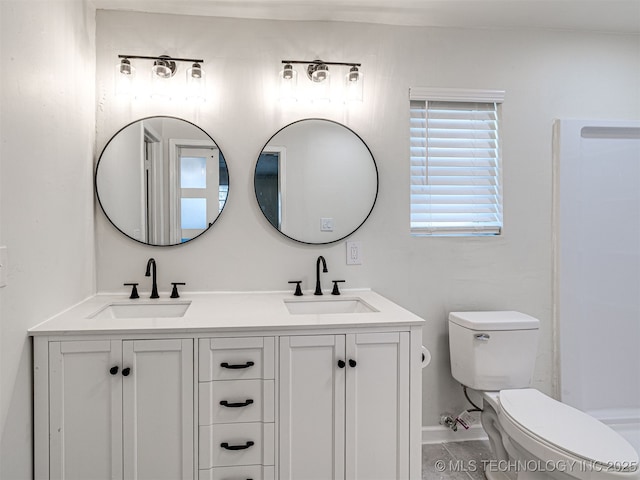 bathroom with double vanity, toilet, and a sink