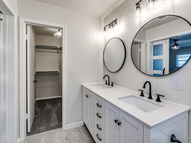 bathroom featuring a sink, a ceiling fan, a spacious closet, and double vanity