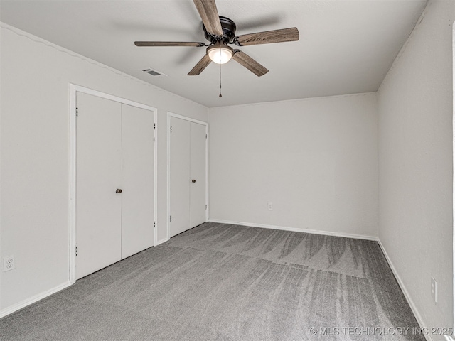 unfurnished bedroom featuring baseboards, visible vents, a ceiling fan, and carpet