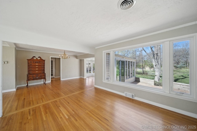 unfurnished living room featuring visible vents, light wood finished floors, and a chandelier