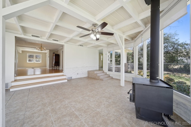 unfurnished sunroom with visible vents, beam ceiling, coffered ceiling, and a wood stove