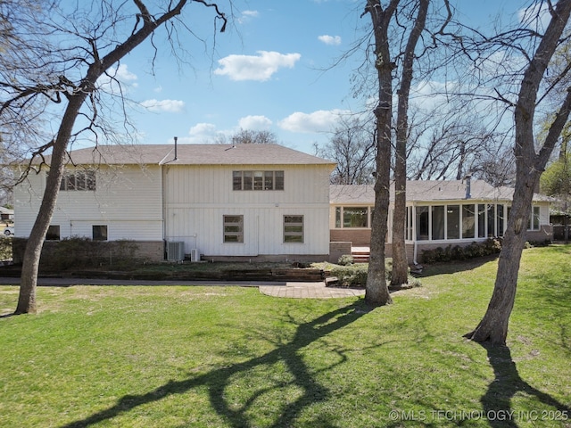 rear view of property featuring central air condition unit, a yard, and a sunroom