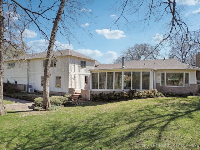 rear view of property with a lawn, central AC unit, a chimney, and a sunroom