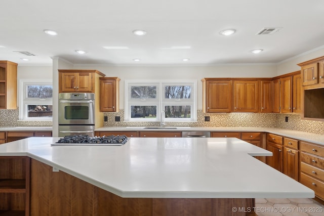 kitchen featuring visible vents, gas stovetop, a sink, light countertops, and a center island