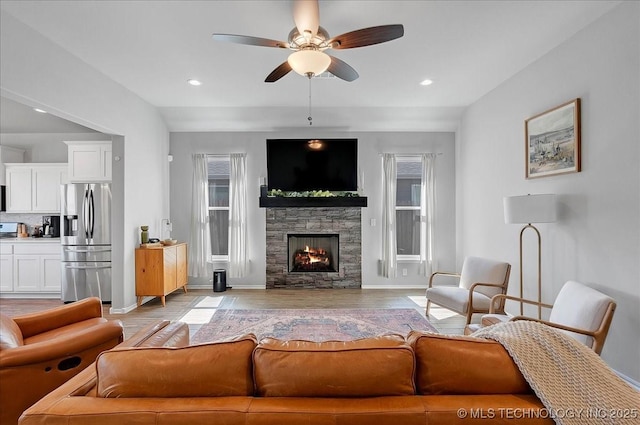 living area with light wood finished floors, baseboards, recessed lighting, a fireplace, and a ceiling fan