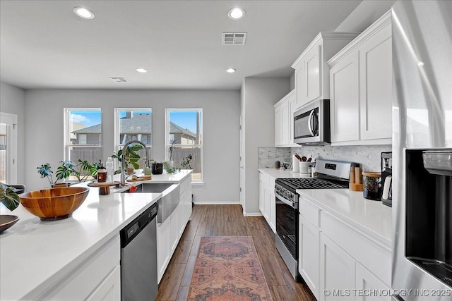 kitchen with tasteful backsplash, visible vents, dark wood finished floors, light countertops, and stainless steel appliances