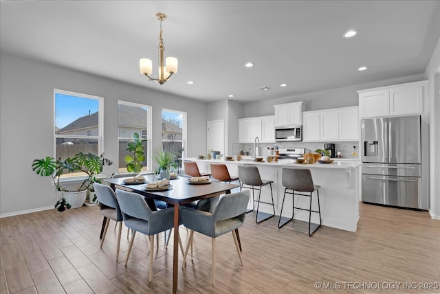 dining space featuring a notable chandelier, recessed lighting, baseboards, and light wood-style floors