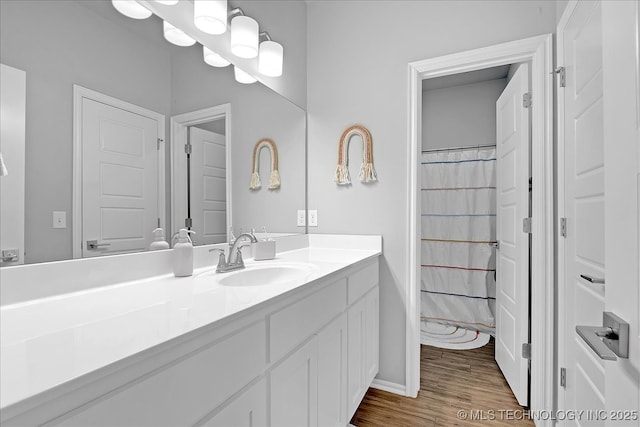 bathroom with vanity, curtained shower, and wood finished floors