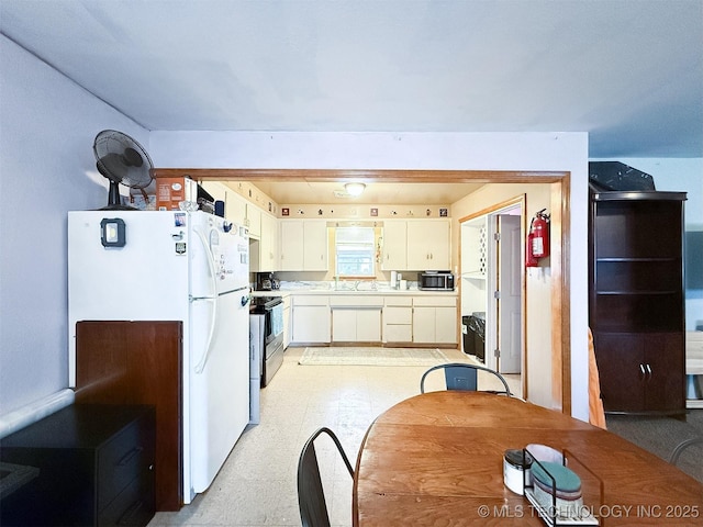 kitchen featuring stainless steel appliances, white cabinetry, light floors, and light countertops