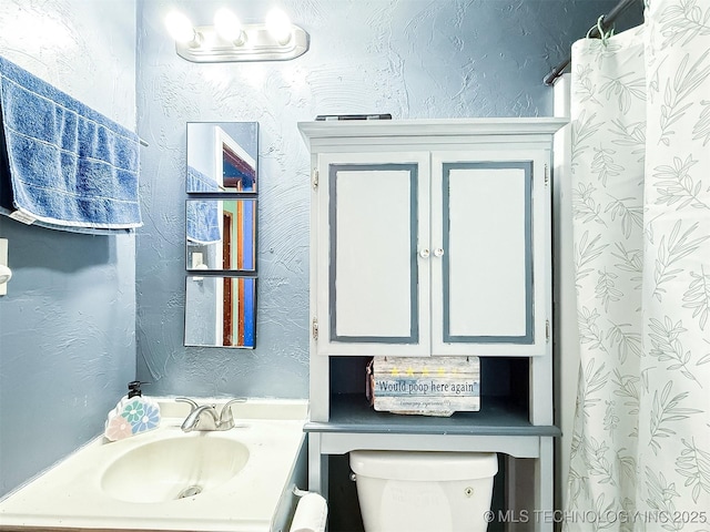 bathroom featuring a shower with shower curtain, toilet, vanity, and a textured wall