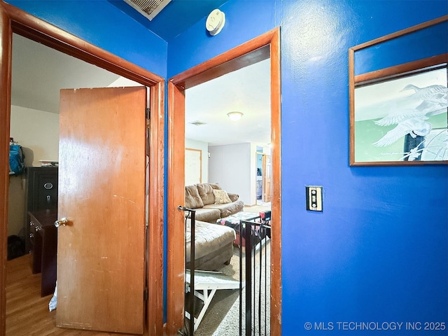 corridor featuring wood finished floors and visible vents