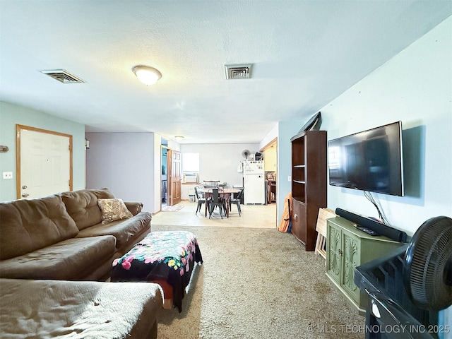 living room featuring visible vents, light colored carpet, and a textured ceiling